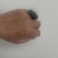 A woman waves her hand and wears a ring topped with a black rubber daisy