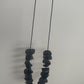 A hand holds a long black necklace