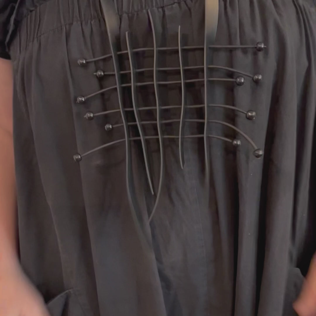 A video showing a woman wearing a grid style rubber necklace