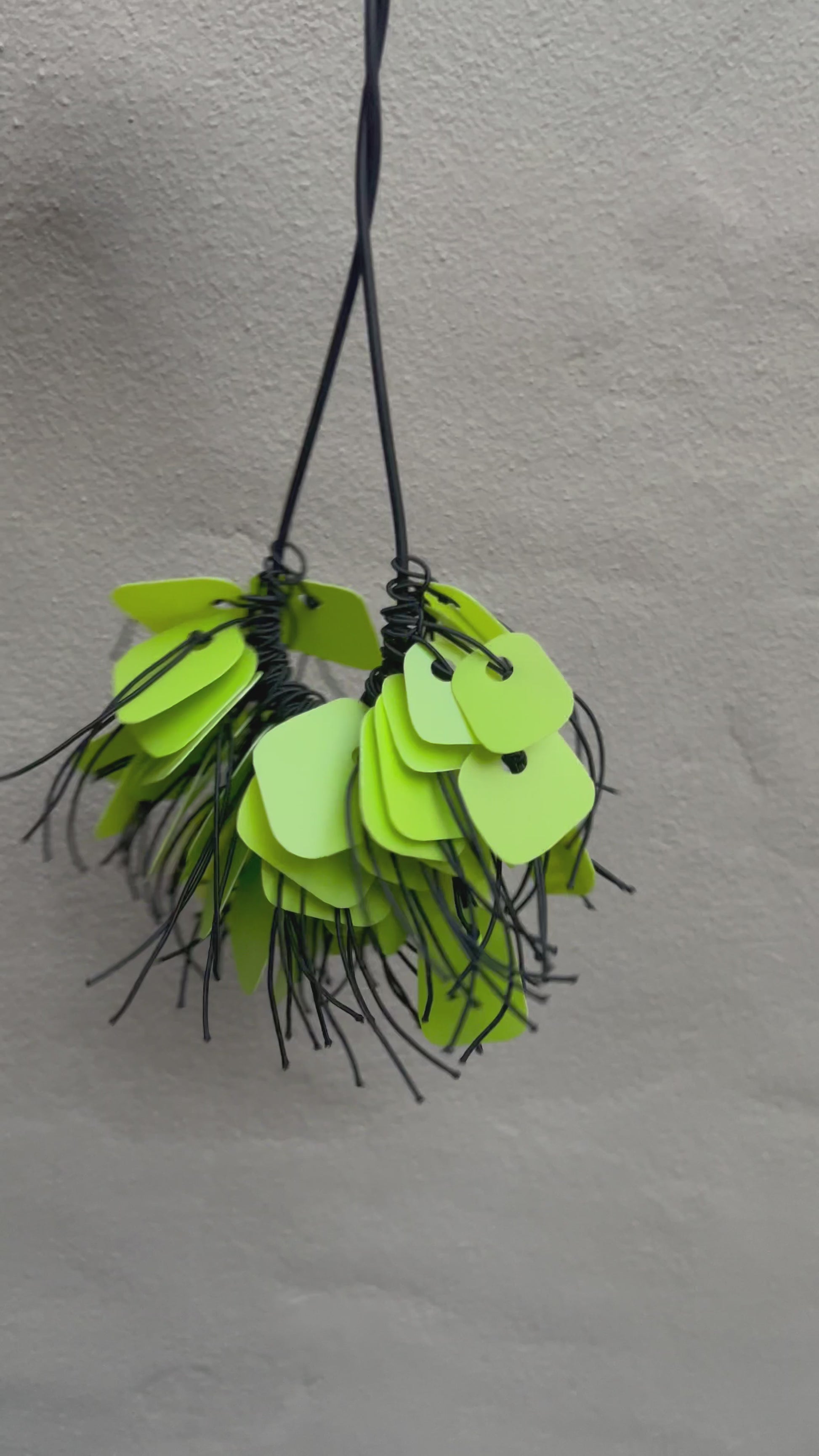 A necklace made from green coloured recycled plastic spins in the sunlight