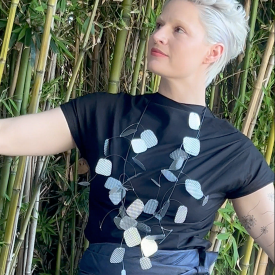 A woman dances slowly wearing a silver necklace, black t-shirt and a beautiful skirt