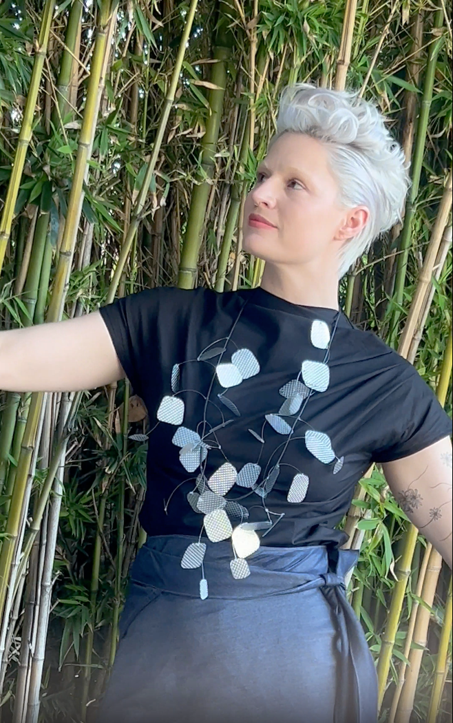 A woman dances slowly wearing a silver necklace, black t-shirt and a beautiful skirt