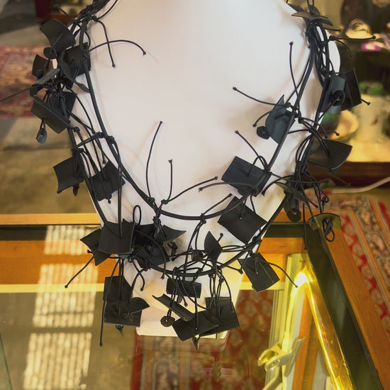 A black chaotically designed contemporary necklace on a mannequin