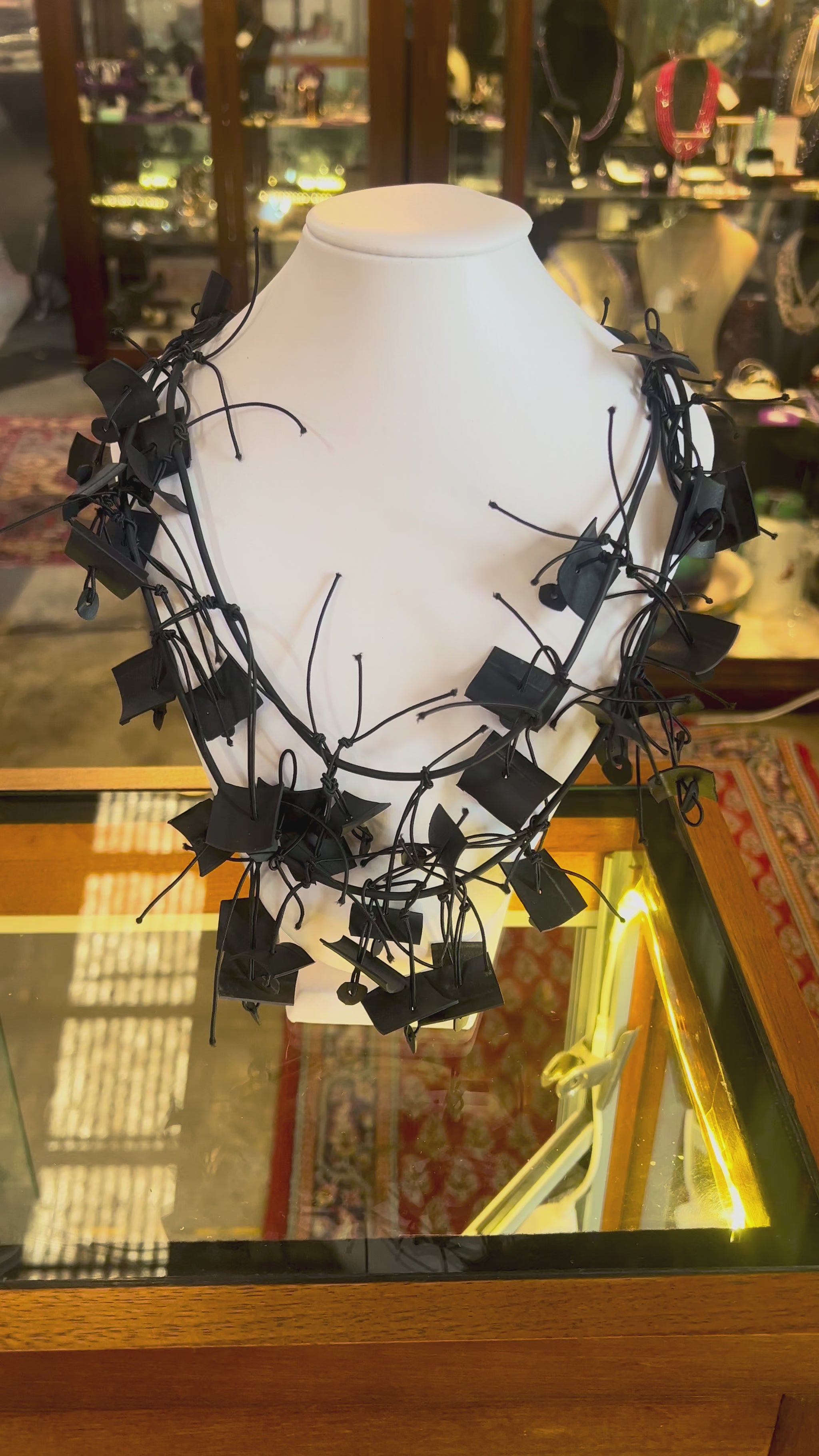 A black chaotically designed contemporary necklace on a mannequin