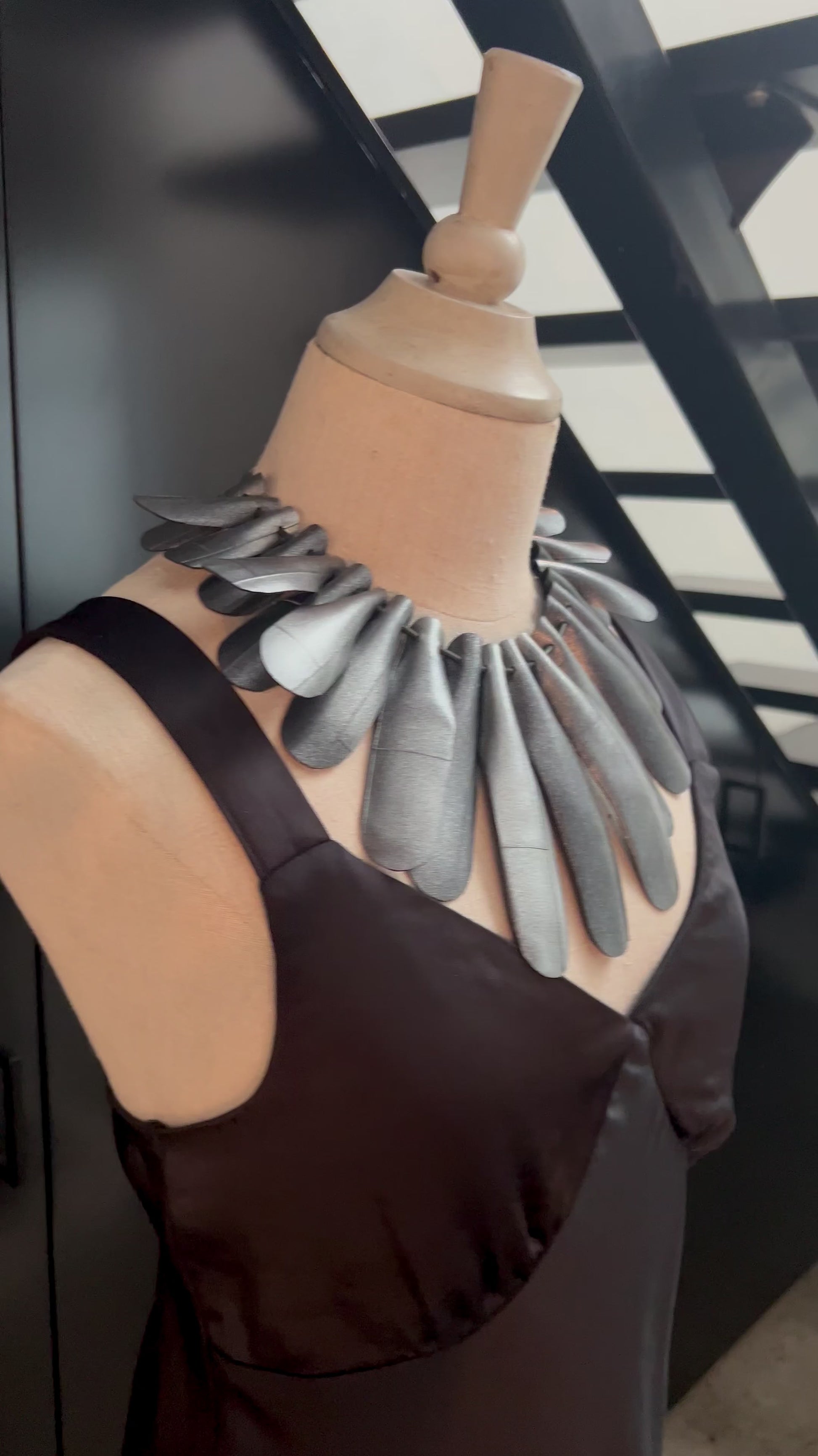 A mannequin wears a large necklace with long silver leaves