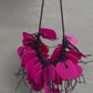 A necklace made from pink coloured recycled plastic spins in the sunlight