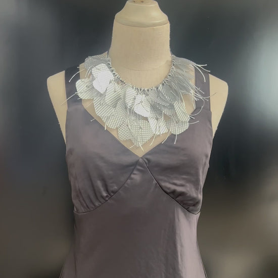 A mannequin wears a large silver tassled necklace