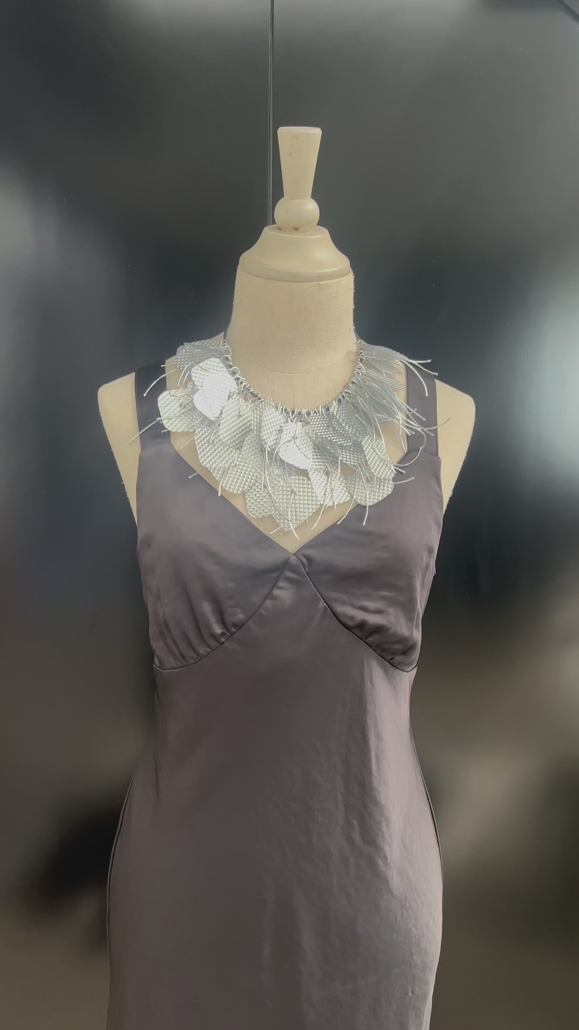 A mannequin wears a large silver tassled necklace