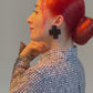 A model wears a pair of black cross stud earrings