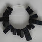 A video of a close up of a large rectangular shaped choker of black rubber
