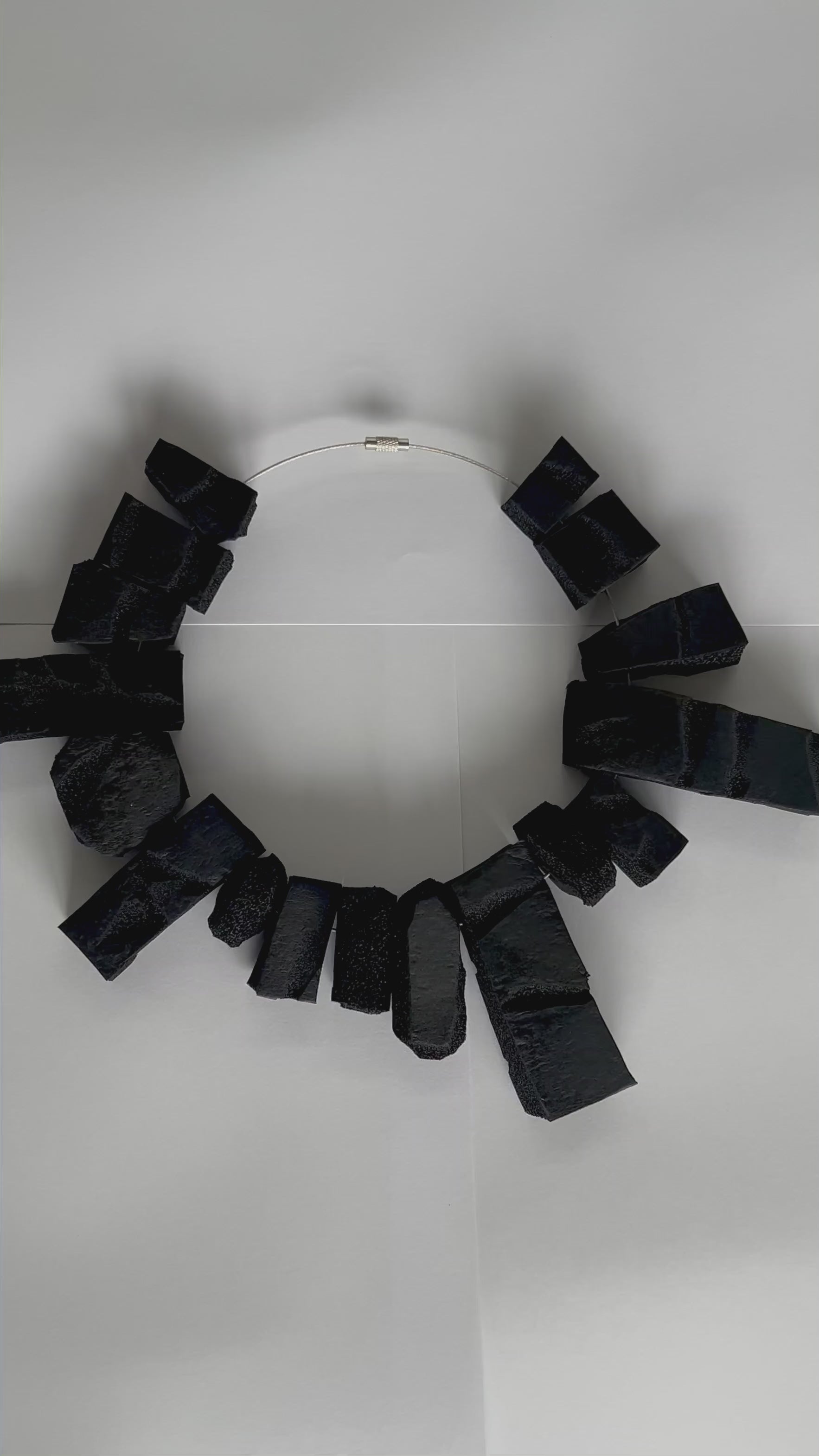 A video of a close up of a large rectangular shaped choker of black rubber