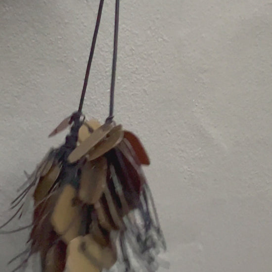A necklace made from recycle bronze coloured plastic spins in the sunlight