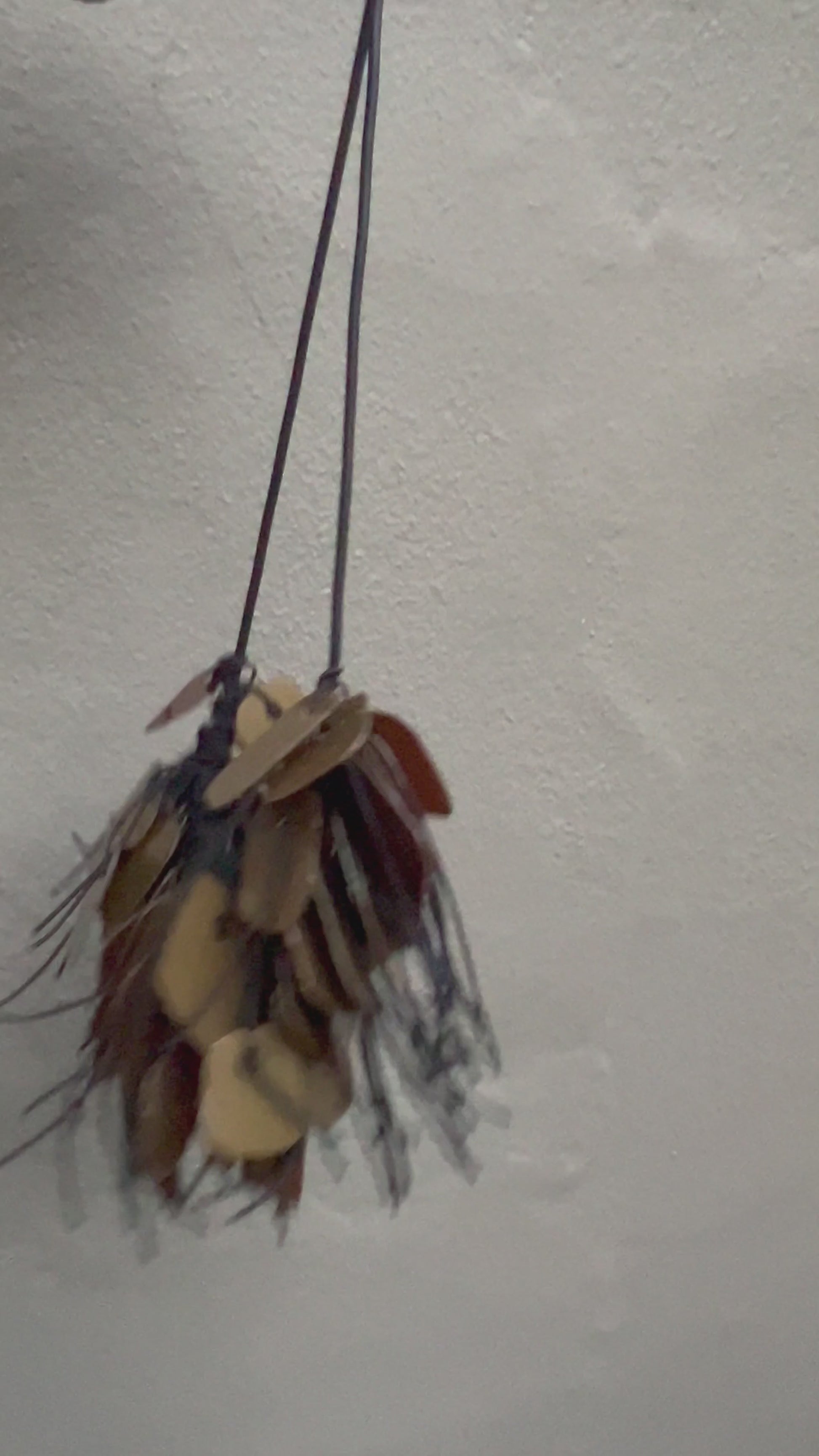 A necklace made from recycle bronze coloured plastic spins in the sunlight