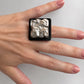 A video of a hand wearing a black and silver square ring