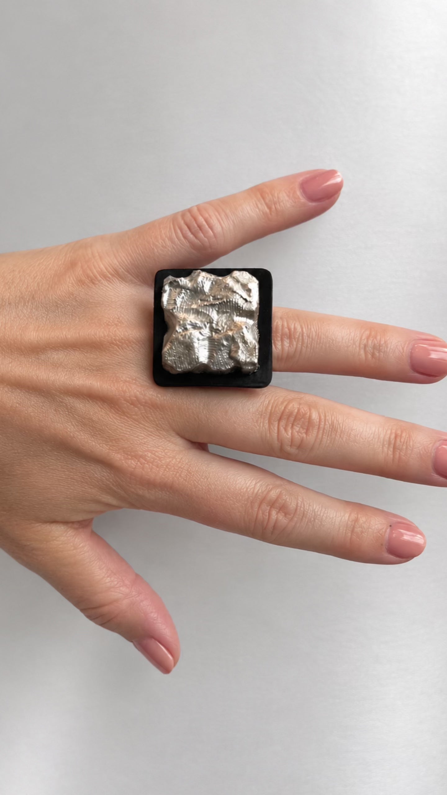 A video of a hand wearing a black and silver square ring