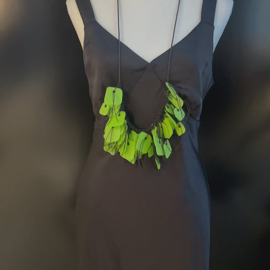 A hand plays with a necklace made from green coloured recycled plastic