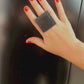 A woman wears a large square black ring made from repurposed rubber