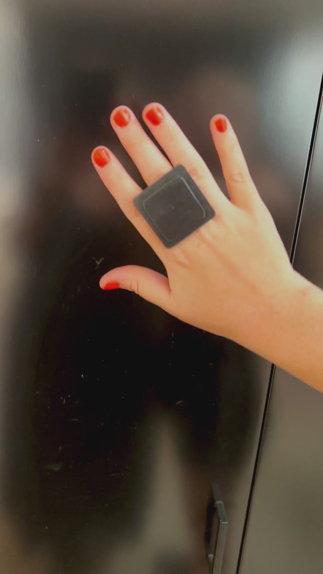 A woman wears a large square black ring made from repurposed rubber